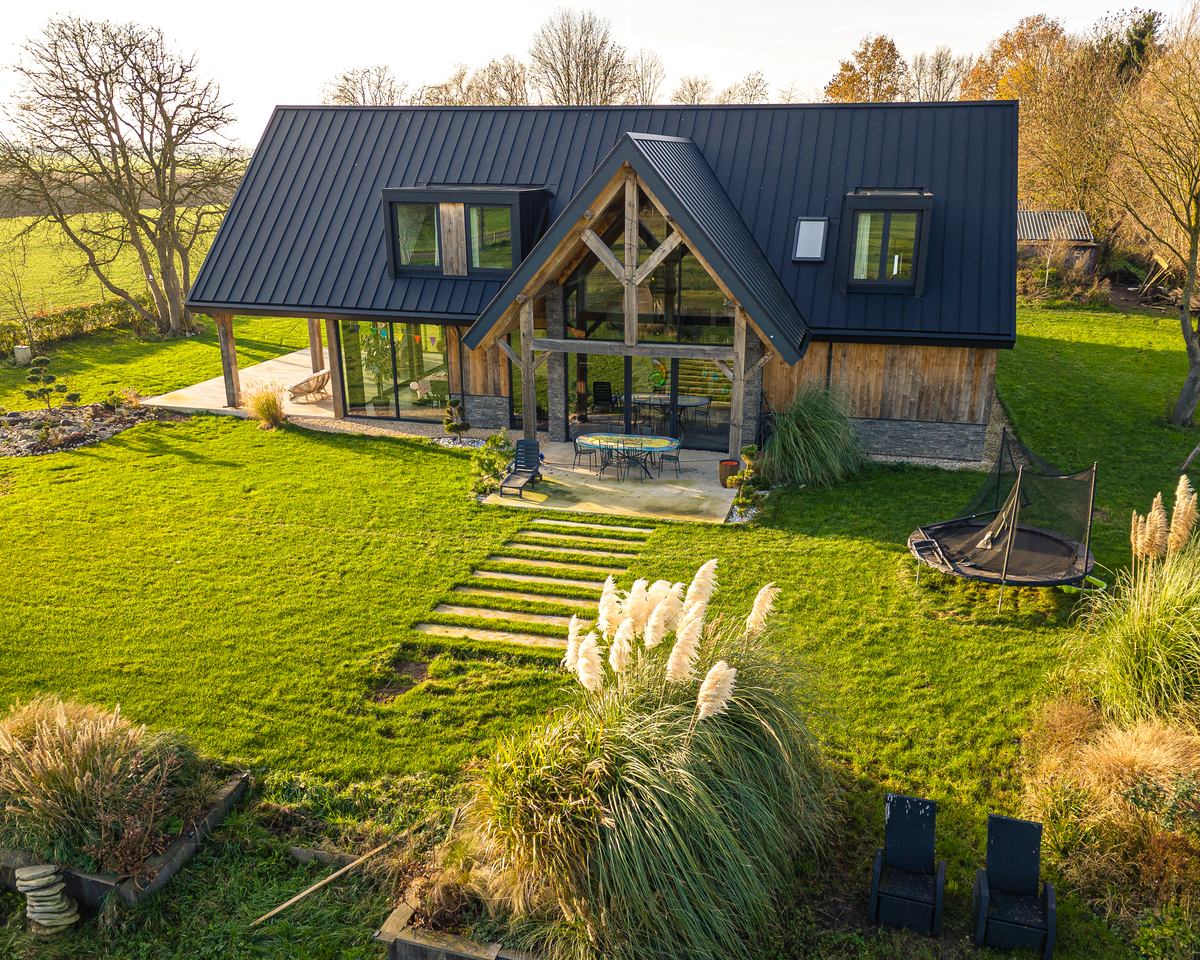 Woning met donker dak en een grote overdekte houten veranda aan de tuin