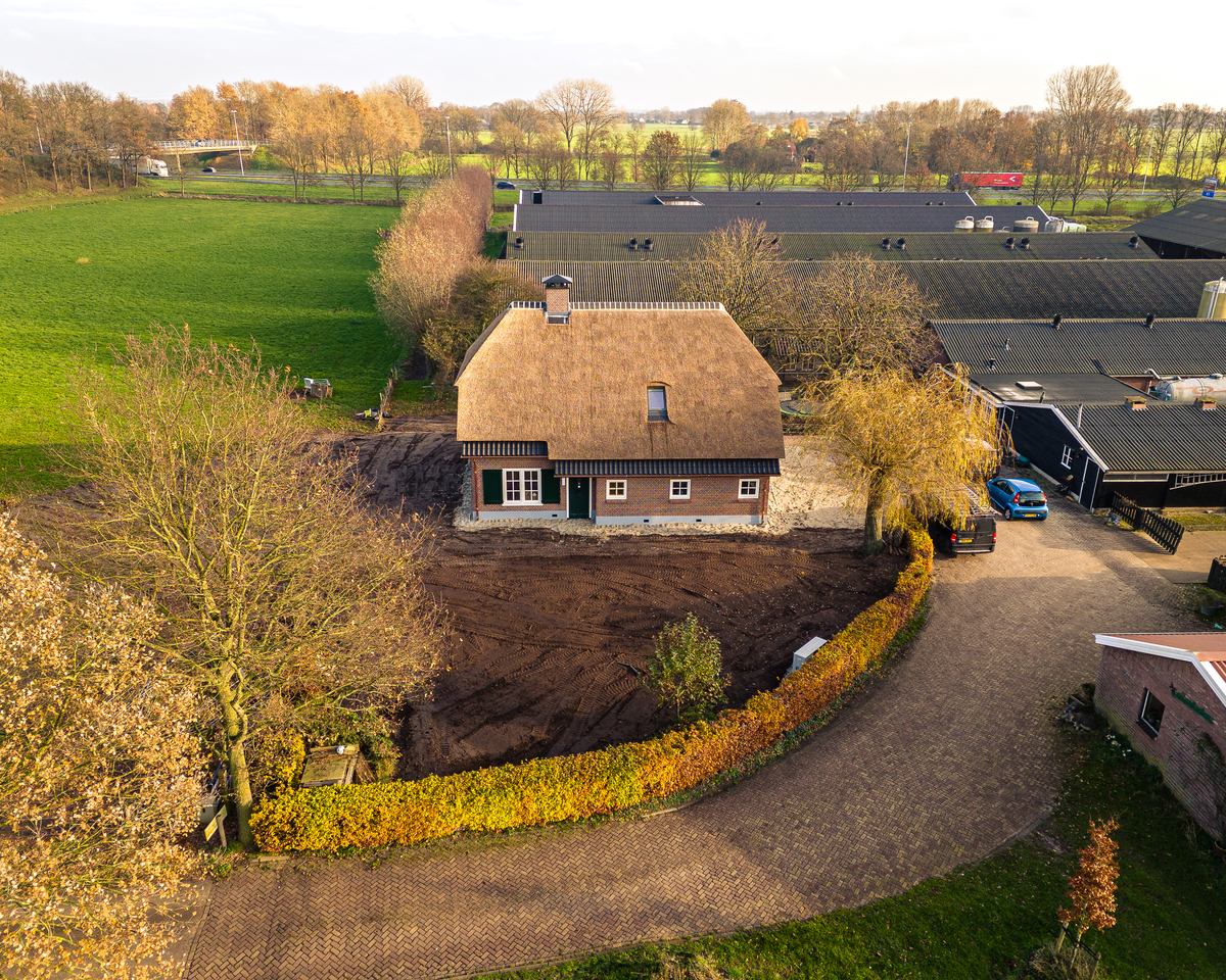 Woning met rieten kap en bakstenen gevel in het avondlicht, gezien van boven