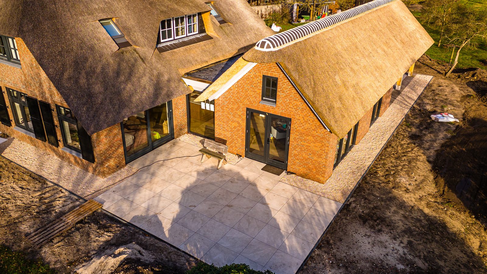 Woning met rieten kap en een nieuw terras van grote tegels, het werk is nog bezig