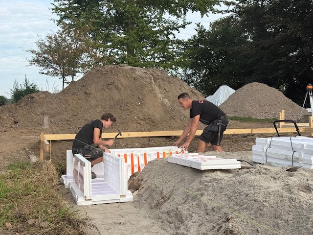 Twee collega's van Groters plaatsen samen de isolatiebekisting voor een fundering