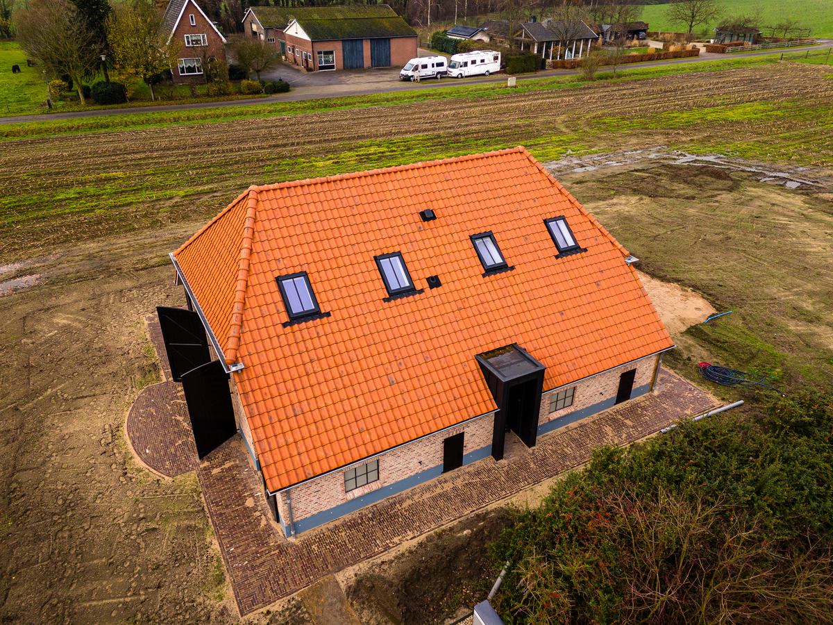 Woning met oranje pannendak in het groen, gezien van boven