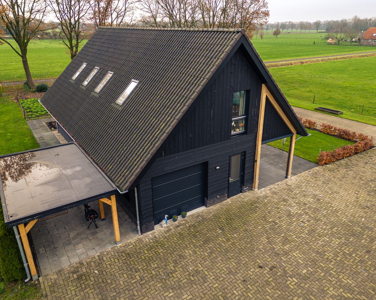 Donkere schuurwoning met zonnepanelen op het dak en een overkapping aan de zijkant