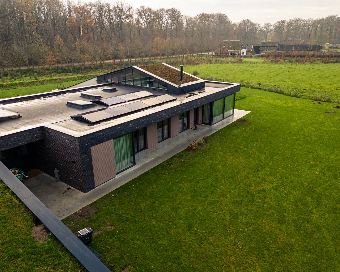 Woning met plat dak, zonnepanelen en dakramen, gezien van boven